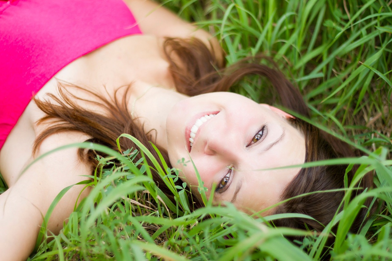 Chica sonriendo tumbada en el campo.