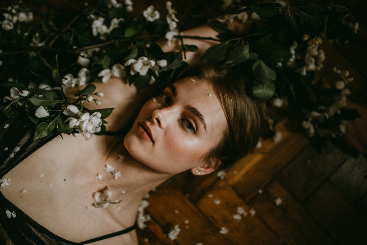 Chica con piel blanca y ojos marrones tumbada entre flores