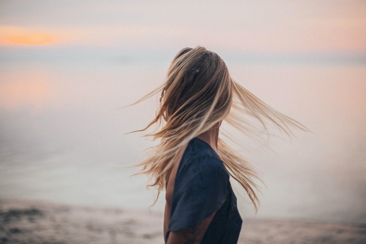 Chica de espaldas moviendo el pelo al viento